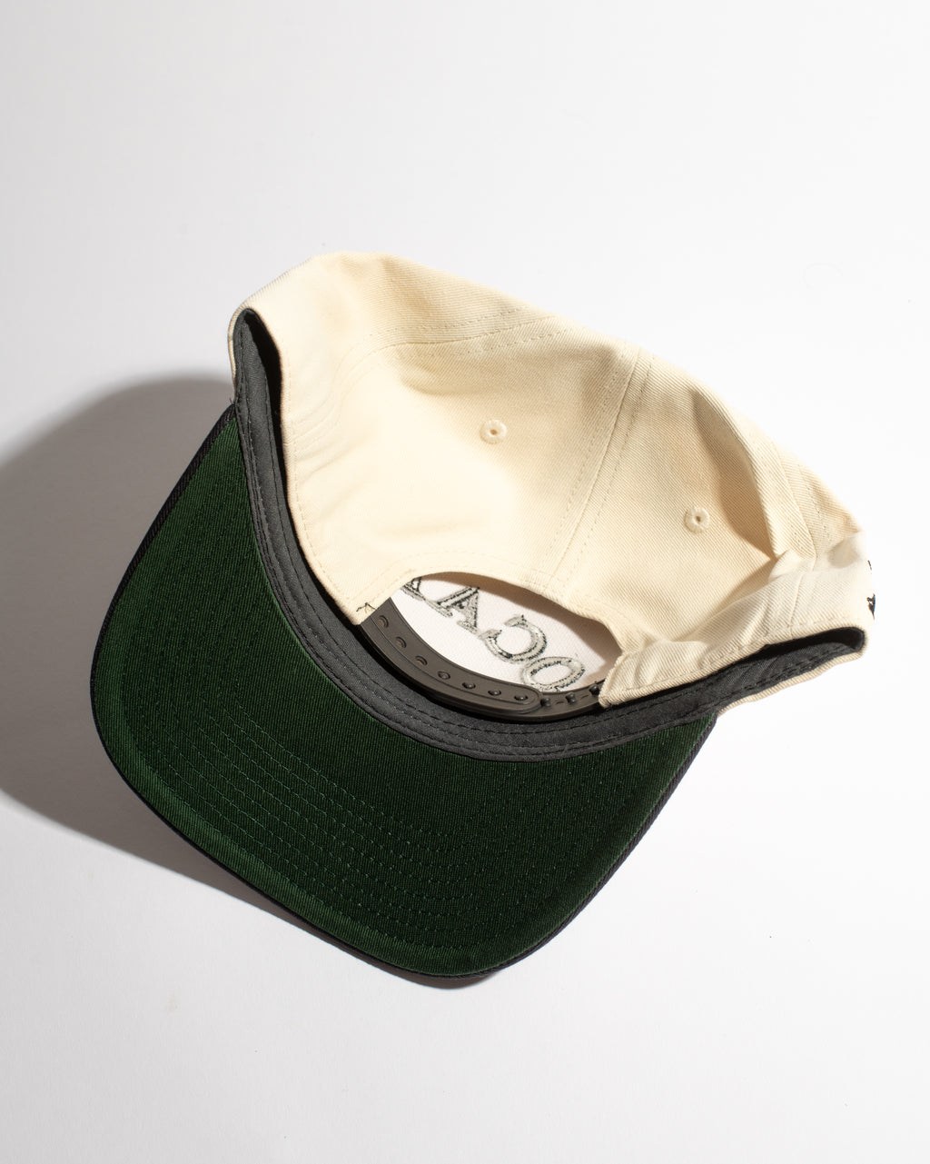 Two baseball caps, one beige and one green, on a light gray background.